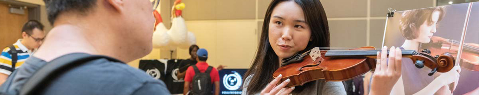 A picture of a girl demonstrating a violin to a man.